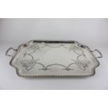 A rectangular plated two-handled tea tray with shaped raised edge and engraved ribbon and bell