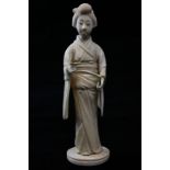 A late 19th, early 20th century Japanese carved ivory okimono of a lady in long dress holding a