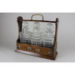 An oak metal mounted tantalus containing three decanters (a/f), 35cm