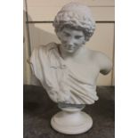 A carved white marble bust of a young man with curly hair and head band on circular plinth base,