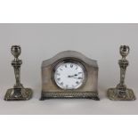 A silver plated mantel clock in domed case, 17cm, and a pair of neo-classical styled candlesticks,