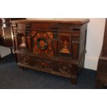 A 17th century oak mule chest with hinged top, the front applied and inlaid decoration with one hung