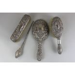 Four Victorian silver backed dressing table items comprising hand mirror, clothes brush, hair