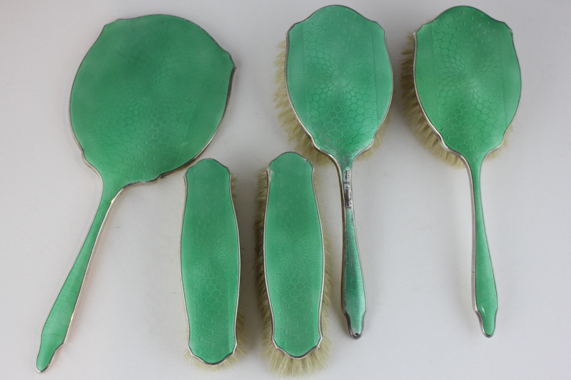 A George V silver and green enamel backed dressing table set comprising hand mirror, two hair