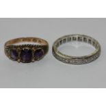 An 18ct white gold and gem set full hoop eternity ring; an amethyst three stone ring