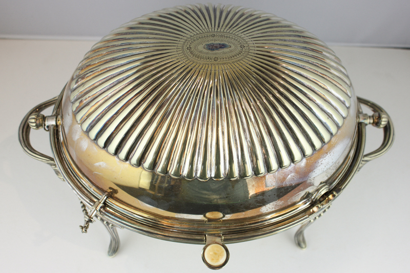 A silver plated revolving oval breakfast dish with strainer and locking pin on four reeded curved