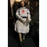 A wooden and sackcloth mannequin figure of a woman with articulating limbs, dressed in a nurse's