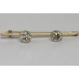 A diamond two stone bar brooch eight claw set with an old cushion and an old cut diamond in white
