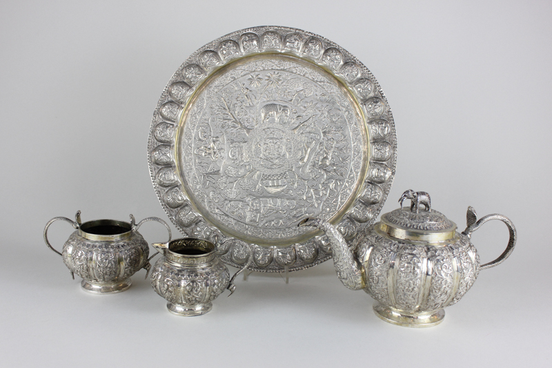 An Indian silver three piece tea set on matching tray, melon fluted, profusely chased with leafy
