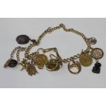A 9ct gold curb link chain hung with a large collection of charms and pendants and coins, 110g