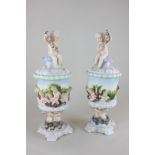 A pair of Sitzendorf porcelain urns and covers, the finial modelled as a cherub holding a garland,