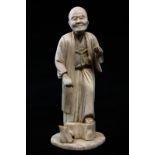 A 19th century Japanese carved ivory okimono of an elderly man standing, wearing long robes, 15cm