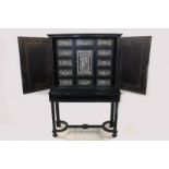 An early 19th century Italian ebonised cabinet on stand with an arrangement of drawers and