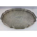 A foreign silver coloured metal tea tray with pierced gallery and engraved centre, on four ball feet