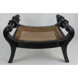 A 19th century Anglo Indian ebony stool, with scrolled supports and flower head handles, cane seat