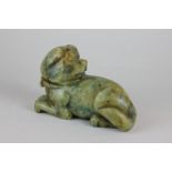 A green stone carving of a dog lying down, 15cm