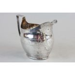 A George III silver cream jug with engraved decorated oval body and monogrammed shield cartouche (