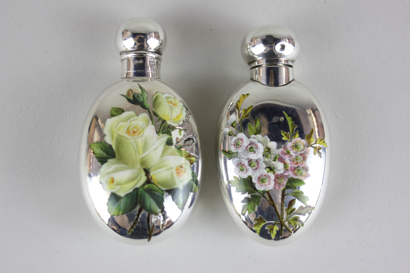 Two Victorian silver and enamel oval scent bottles, one monogrammed and enamelled with roses, the