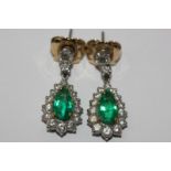 A pair of emerald and diamond drop earrings, the pear shaped stones within a border of graduated