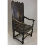 A 17th century oak wainscot chair with plain panelled back and wooden seat on turned legs (NC)