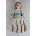 A Kamer and Reinhart porcelain head doll with blond hair, blue eyes and composite limbs, in lace