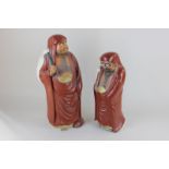 Two Japanese pottery figures of Bodhidharma with fly swatters wearing robes, tallest 44cm