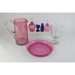 A cranberry glass jug, two scent bottles and a tray, together with a rummer blue glass scent