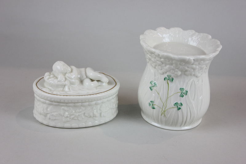 A Belleek porcelain oval box, the corner modelled as a sleeping child, together with a small Belleek