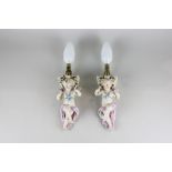 A pair of Continental porcelain wall lights modelled as winged cherubs carrying baskets of