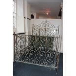 A gilt painted wrought iron double bed with ornately scrolled headboard, side board and two higher
