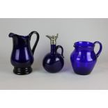 A silver plate mounted blue glass claret jug, together with two other blue glass jugs