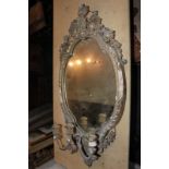 A giltwood and gesso oval girondelle wall mirror with shell surmount and three light candle
