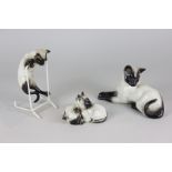 Three Beswick Siamese cat figures including lying, facing left (1558A), kittens curled together (