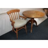 A circular pine table on tripod base, together with a pine elbow chair