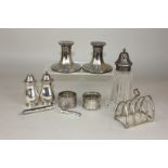 A silver toast rack, two silver napkin rings, cheroot holder case, egg timer, plated candlesticks,