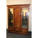 An Edwardian inlaid mahogany break-front wardrobe with double mirrored doors flanking panelled