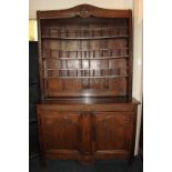 A French oak dresser with three curved shelves above two carved panel doors enclosing two shelves,