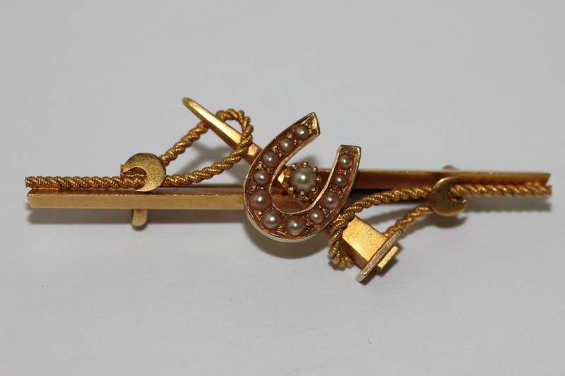A gold and split pearl horseshoe bar brooch