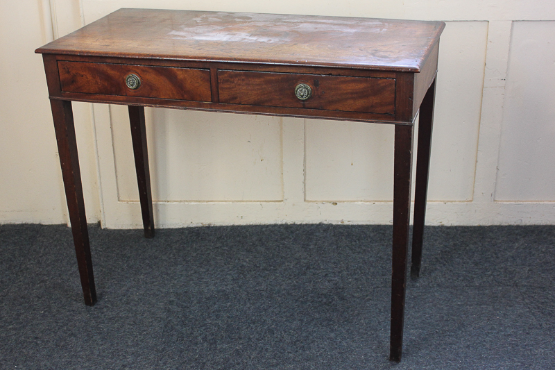 A mahogany two-drawer side table with lion mask handles, on square tapered legs, 94cm