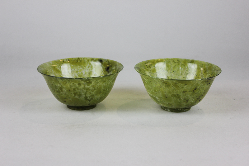 A pair of Chinese green jade bowls with flared rims on short bases, 10cm diameter