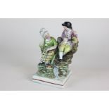 A 19th century Staffordshire pottery pearlware figure of a man and woman seated on rocks, 17cm high