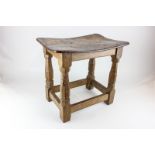 A Robert Mouseman Thompson oak stool with curved top and octagonal legs separated by four