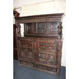 A 19th century carved oak court cupboard with raised panelled back supported by maidens above two