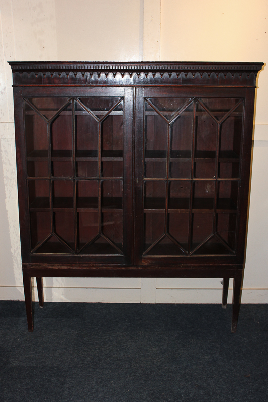 An early 20th century bookcase with panel glazed doors enclosing three shelves, on square tapered
