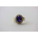 A tanzanite and diamond cluster ring the oval stone within a border of two rows of similar brilliant