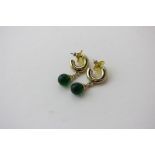 A pair of hoop earrings loose hung with a green paste bead