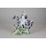 An early 19th century Staffordshire pottery figure of a man riding a horse naively decorated in