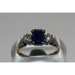 A synthetic sapphire ring set with an eight cut diamond to each shoulder in platinum on 18ct gold