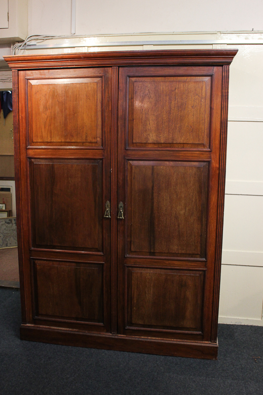 An Edwardian mahogany wardrobe with panelled double doors enclosing hanging compartment and shelves,