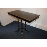 A Victorian ebonised card table with brass edging, beading and inlay and gilt decoration, on four